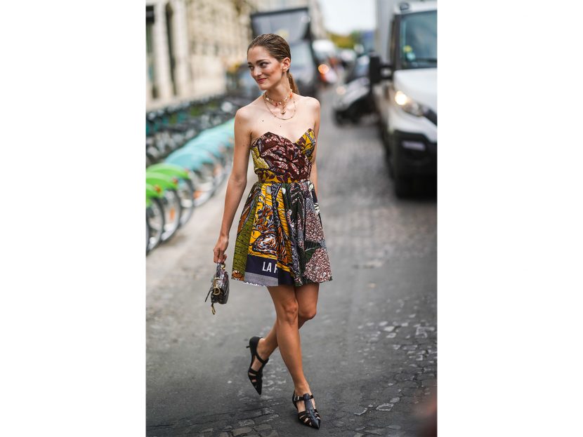 Sofia Sanchez de Betak wears necklaces, a colorful African design wax Dior bustier dress, a python pattern Dior bag, black T-strap pointy heeled sandals, outside Dior, during Paris Fashion Week -Haute Couture Fall/Winter 2019/2020, on July 01, 2019 in Paris, France.